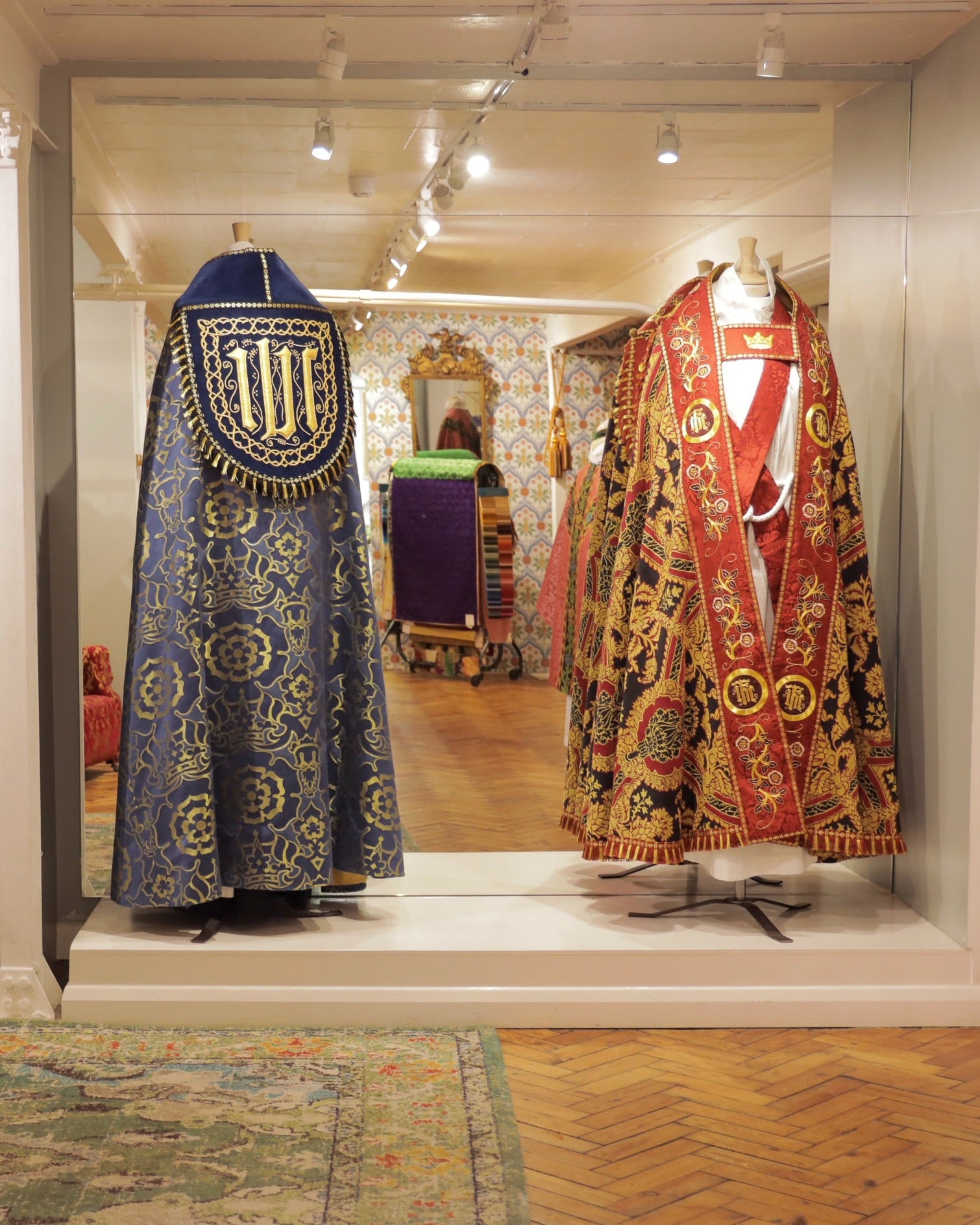 Two ornate copes displayed in Watts' showroom with a mirror reflecting the interior.